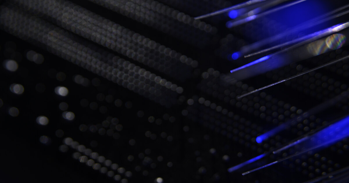 Optical fiber cables connected to network switch hardware in a dark server rack