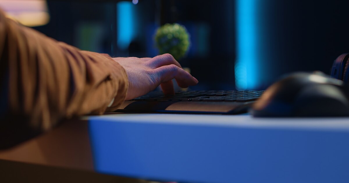 Hands typing on a laptop keyboard in a dimly lit workspace, running backup commands