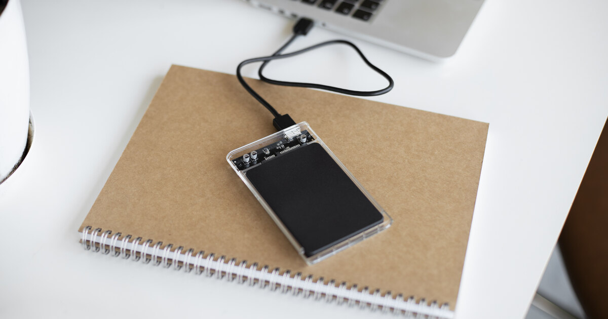 External SSD drive connected to a laptop on a desk for offsite backup storage